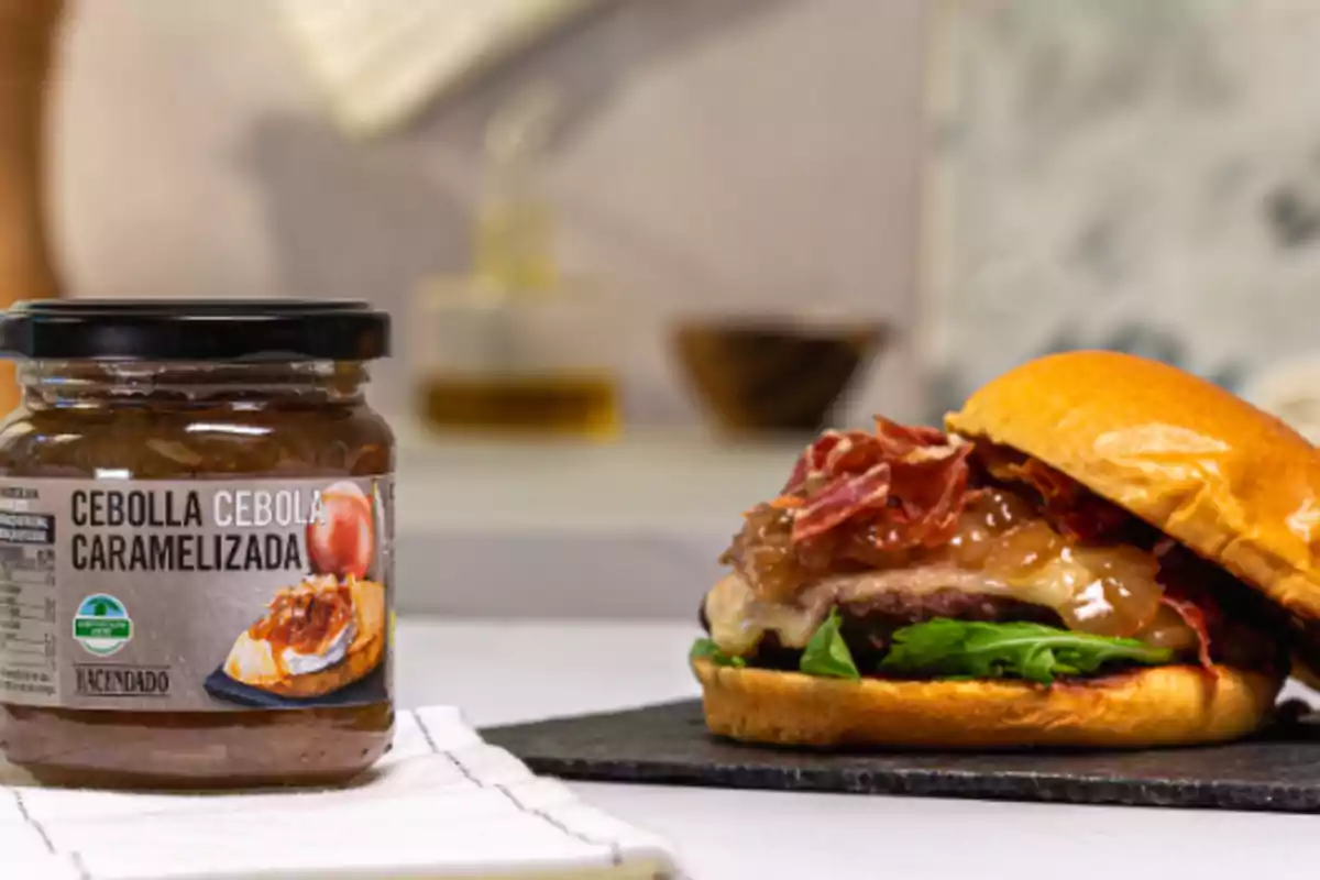 Un flascó de ceba caramel·litzada amb una hamburguesa amb ingredients frescos sobre una superfície de pissarra. Un flascó de ceba caramel·litzada amb una hamburguesa amb ingredients frescos sobre una superfície de pissarra.