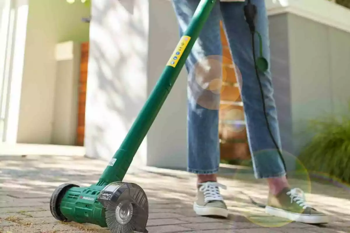 Una persona utilitzant una eina elèctrica de jardineria amb un raspall giratori en un camí pavimentat. Una persona utilitzant una eina elèctrica de jardineria amb un raspall giratori en un camí pavimentat.