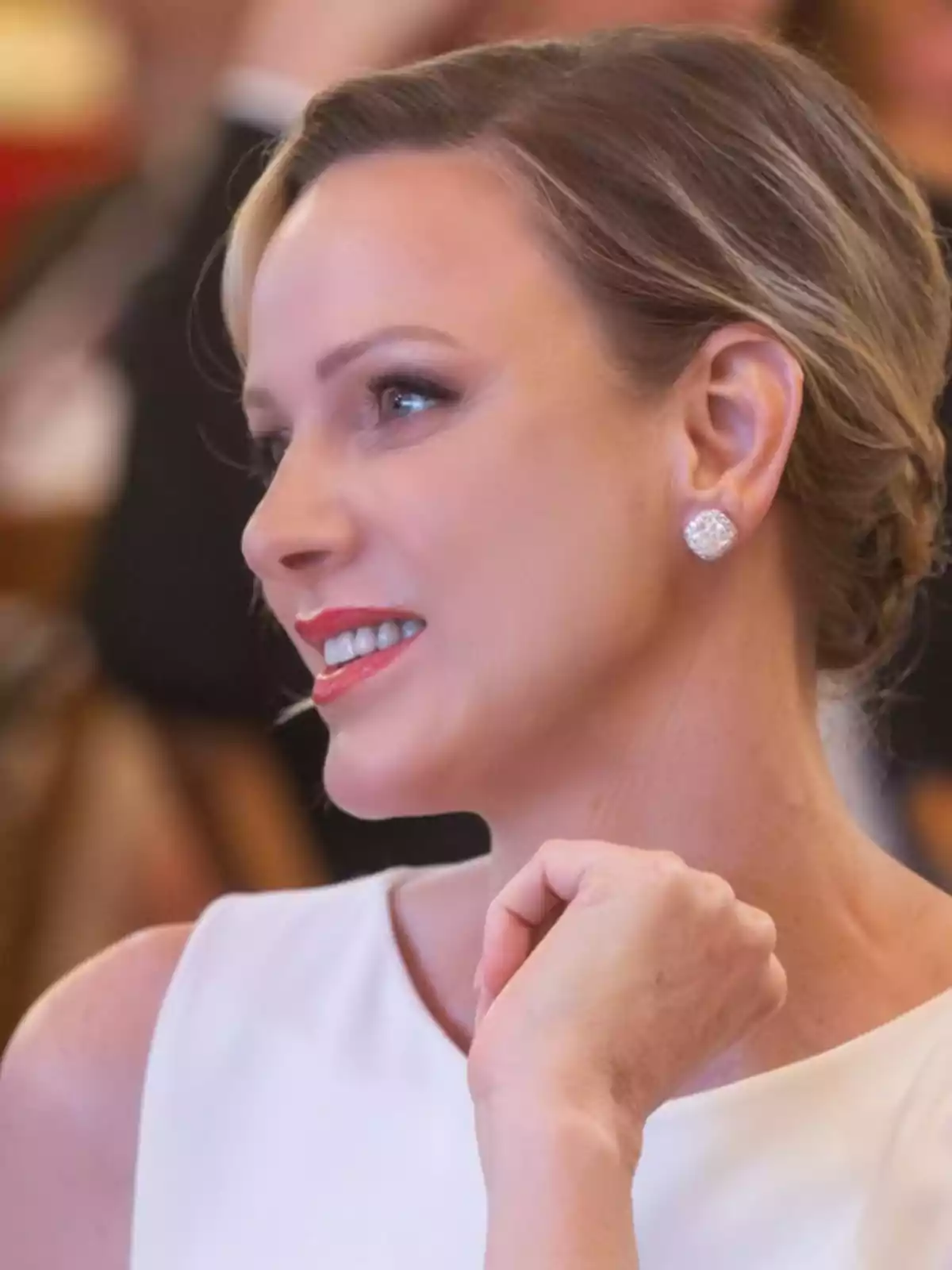 Una persona somrient elegantment amb un vestit blanc i arracades brillants. Una persona somrient elegantment amb un vestit blanc i arracades brillants.