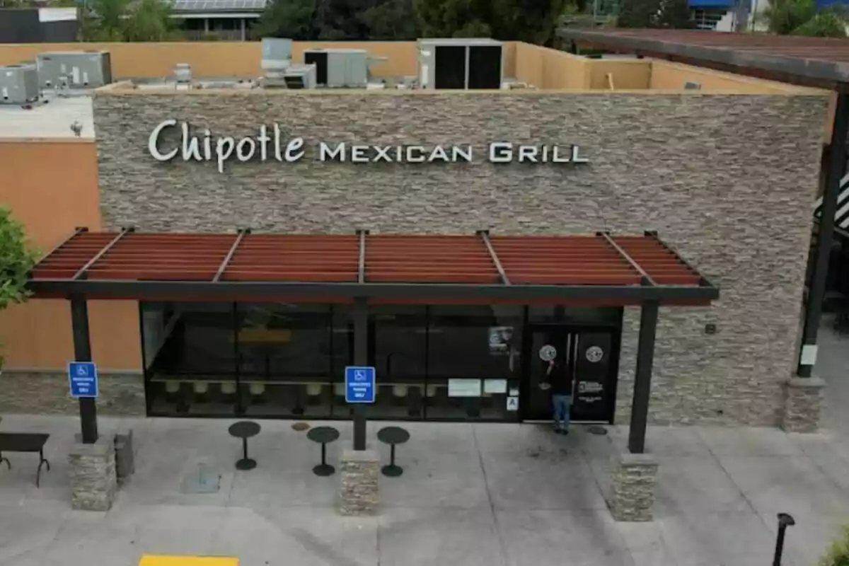 Facade of a Chipotle Mexican Grill restaurant with a person entering through the main door and two handicap parking signs in front Facade of a Chipotle Mexican Grill restaurant with a person entering through the main door and two handicap parking signs in front