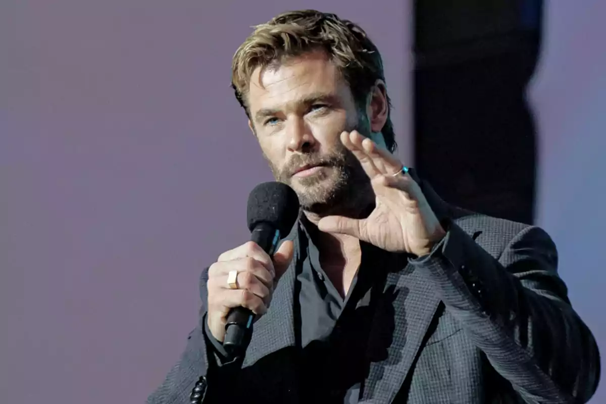 Chris Hemsworth holds a microphone while gesturing with his hand. Chris Hemsworth holds a microphone while gesturing with his hand.