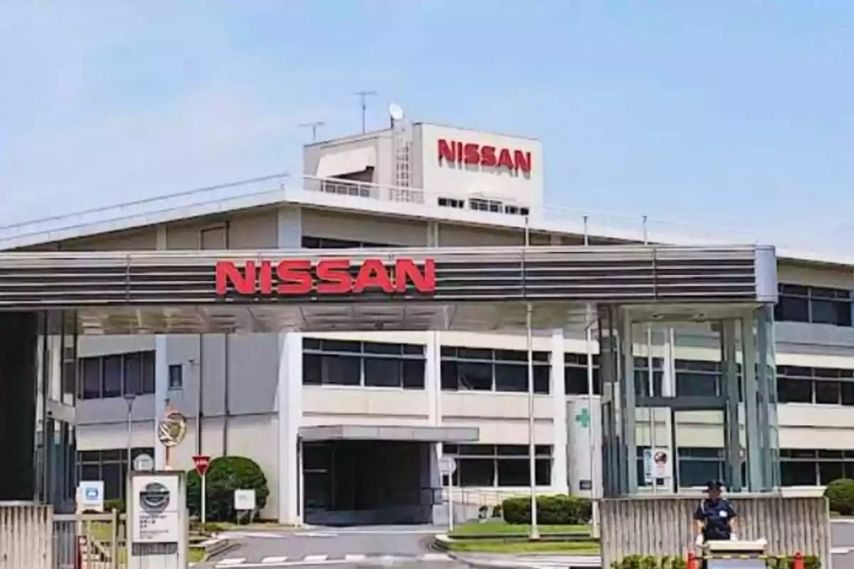 Fachada de una planta industrial de Nissan con el logo en letras rojas sobre la entrada principal