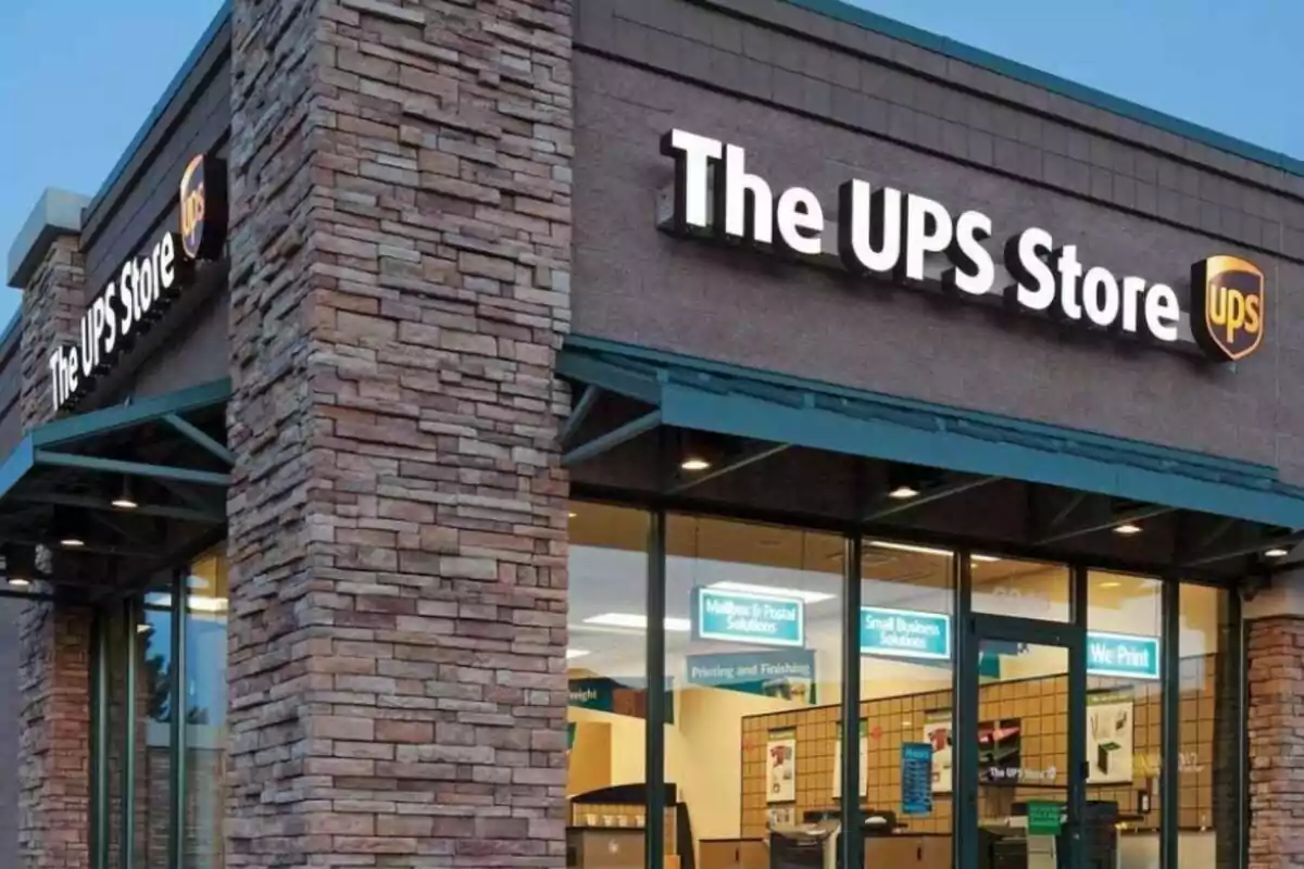Fachada de una tienda de UPS con letrero iluminado y ventanales grandes Fachada de una tienda de UPS con letrero iluminado y ventanales grandes
