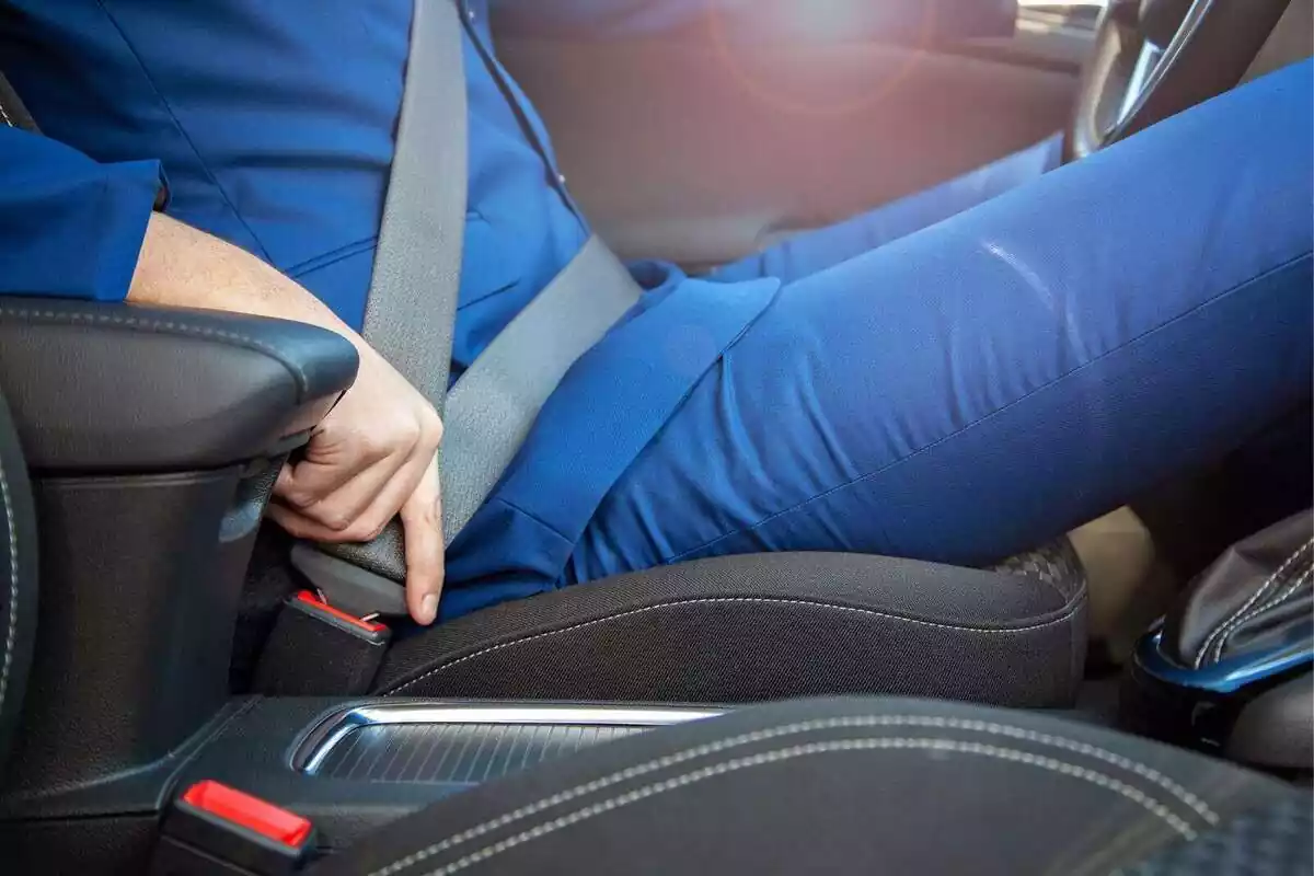 Primer pla d'una persona posant-se el cinturó de seguretat en un coche