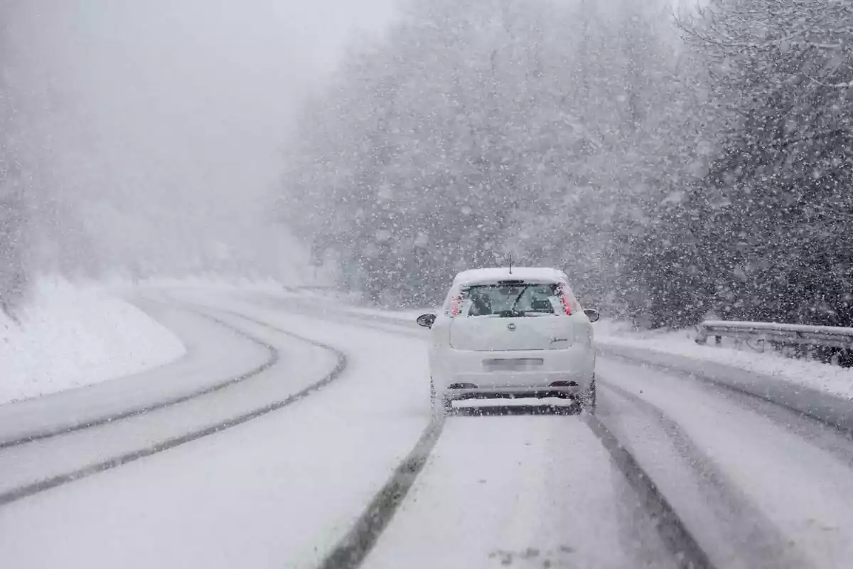 Un cotxe travessant una forta nevada en una carreta a Galícia amb tot cobert amb diversos centímetres