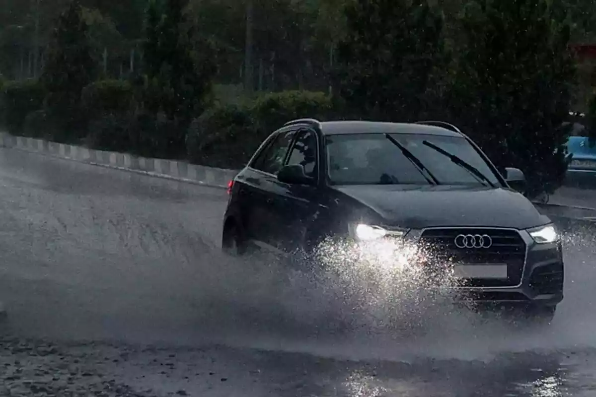 Un cotxe travessant un toll d'aigua al mig d'una tempesta