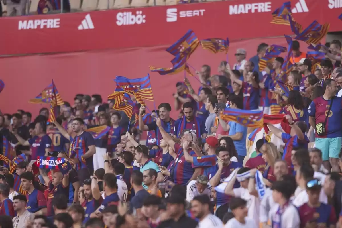 Aficionats en un estadi animant amb banderes i bufandes del FC Barcelona. Aficionats en un estadi animant amb banderes i bufandes del FC Barcelona.