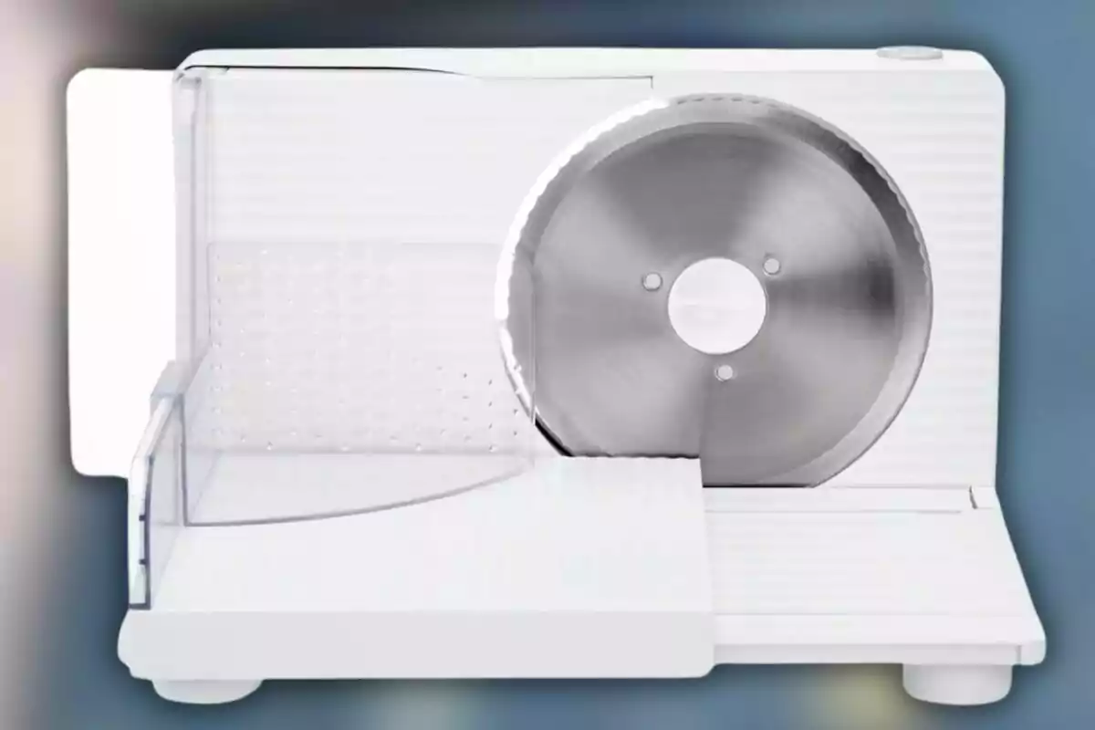 Un tallador d'aliments elèctric amb una fulla circular d'acer inoxidable i una base blanca. Un tallador d'aliments elèctric amb una fulla circular d'acer inoxidable i una base blanca.