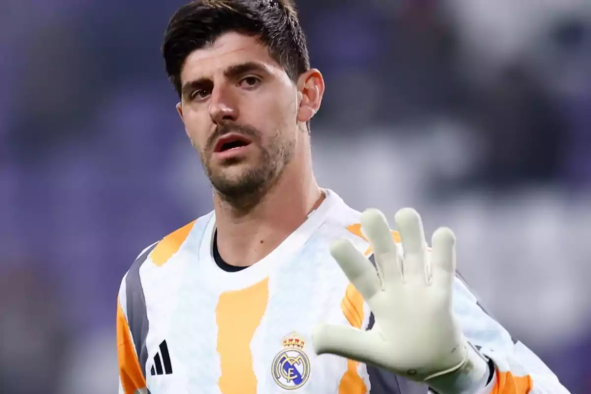 Un futbolista amb uniforme de porter del Reial Madrid aixeca la mà amb un guant blanc. Un futbolista amb uniforme de porter del Reial Madrid aixeca la mà amb un guant blanc.