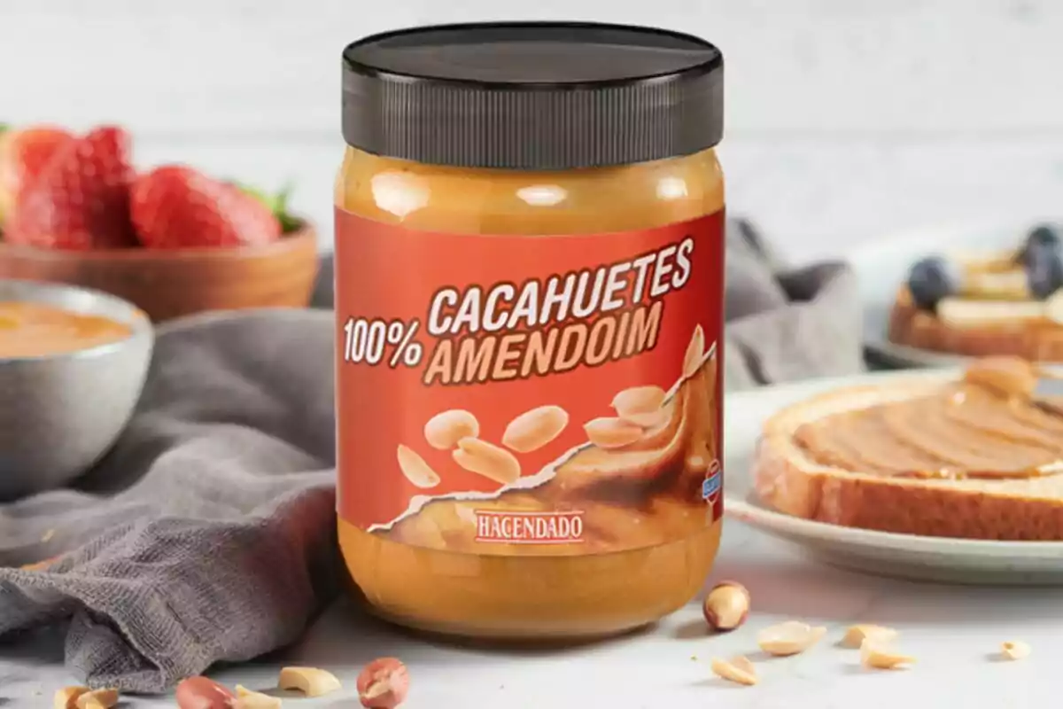 Un pot de crema de cacauet de Mercadona sobre una taula amb maduixes i pa untat al fons. Un pot de crema de cacauet de Mercadona sobre una taula amb maduixes i pa untat al fons.