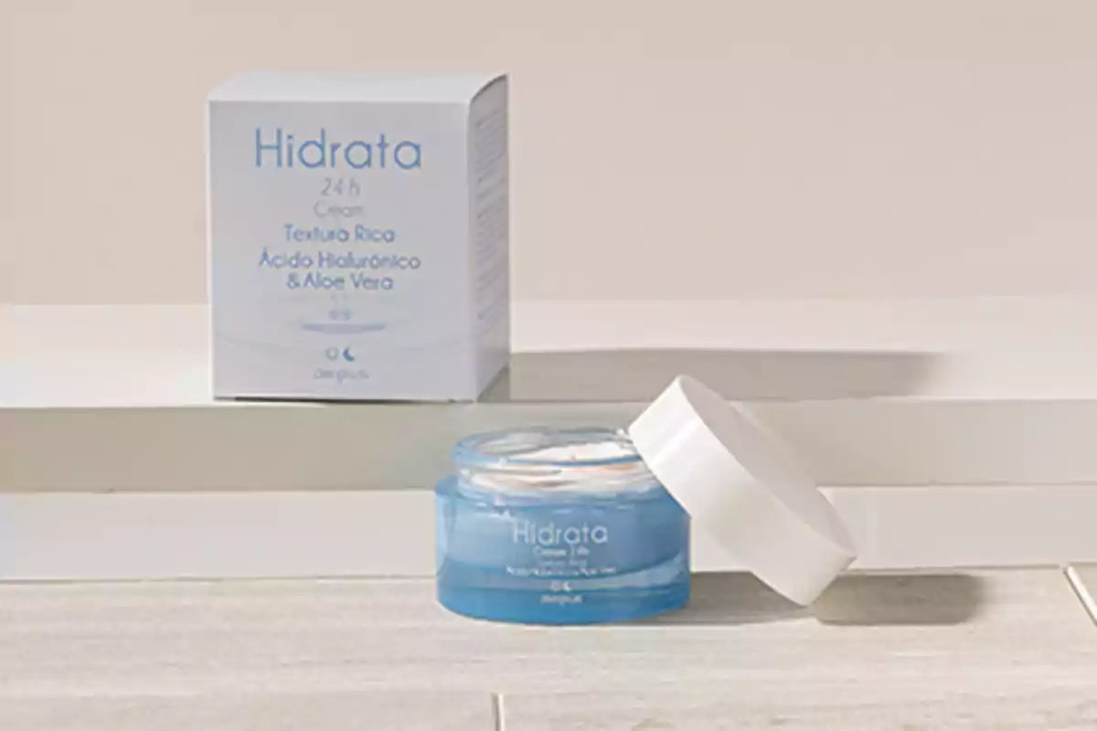 Crema hidratant amb àcid hialurònic i àloe vera en envàs blau al costat de la seva caixa. Crema hidratant amb àcid hialurònic i àloe vera en envàs blau al costat de la seva caixa.