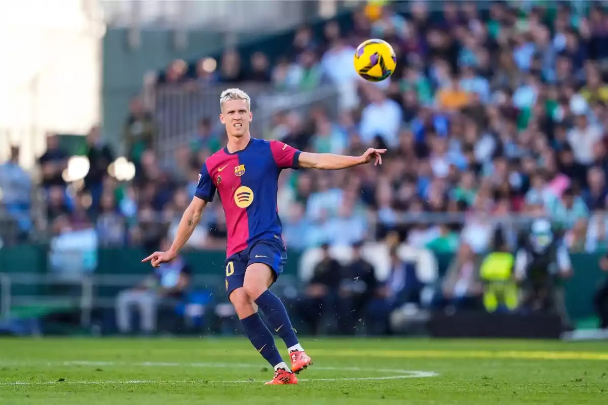 Un jugador de fútbol con uniforme azul y rojo está en el campo durante un partido, concentrado en el balón que está en el aire. Un jugador de fútbol con uniforme azul y rojo está en el campo durante un partido, concentrado en el balón que está en el aire.