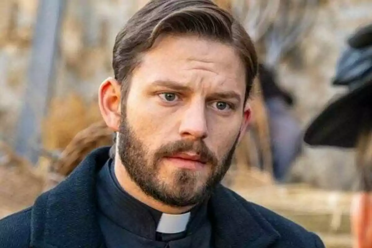 Imatge de l’actor Daniel Schröder amb barba i cabell curt vestit amb sotana negra i collet blanc mirant cap al davant amb expressió seriosa. Imatge de l’actor Daniel Schröder amb barba i cabell curt vestit amb sotana negra i collet blanc mirant cap al davant amb expressió seriosa.