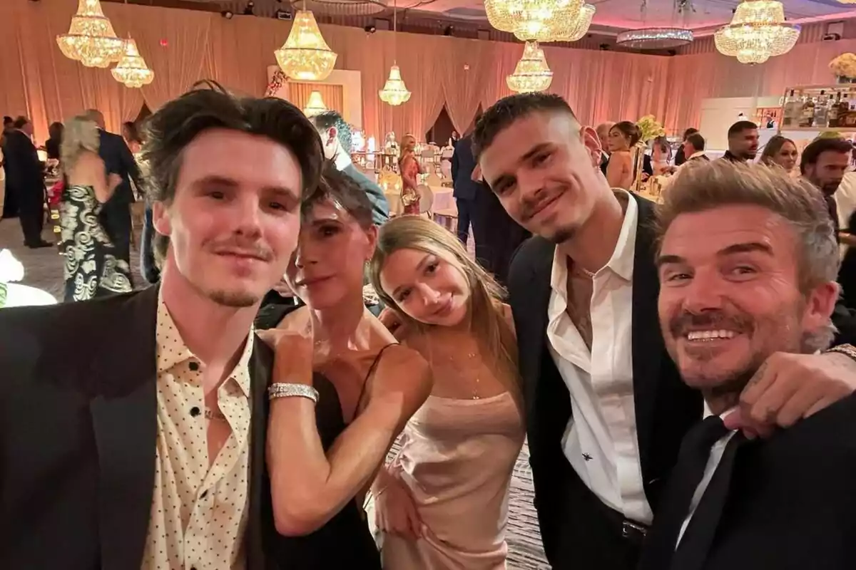 Un grup de persones posant per a una selfie en un esdeveniment elegant amb llums d'aranya al fons. Un grup de persones posant per a una selfie en un esdeveniment elegant amb llums d'aranya al fons.