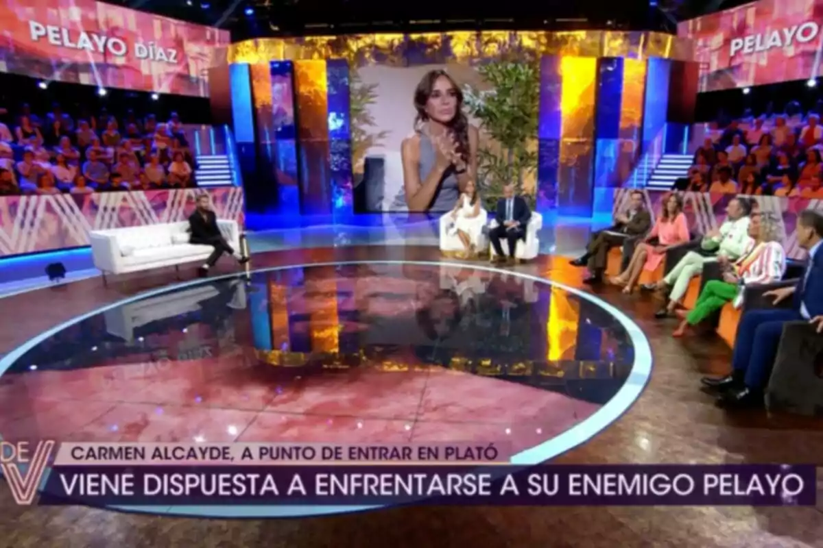 Un plató de televisió amb públic i diversos presentadors asseguts en sofàs mentre una gran pantalla mostra la imatge d’una dona. Captura de ‘¡¡De Viernes!’ Un plató de televisió amb públic i diversos presentadors asseguts en sofàs mentre una gran pantalla mostra la imatge d’una dona. Captura de ‘¡¡De Viernes!’