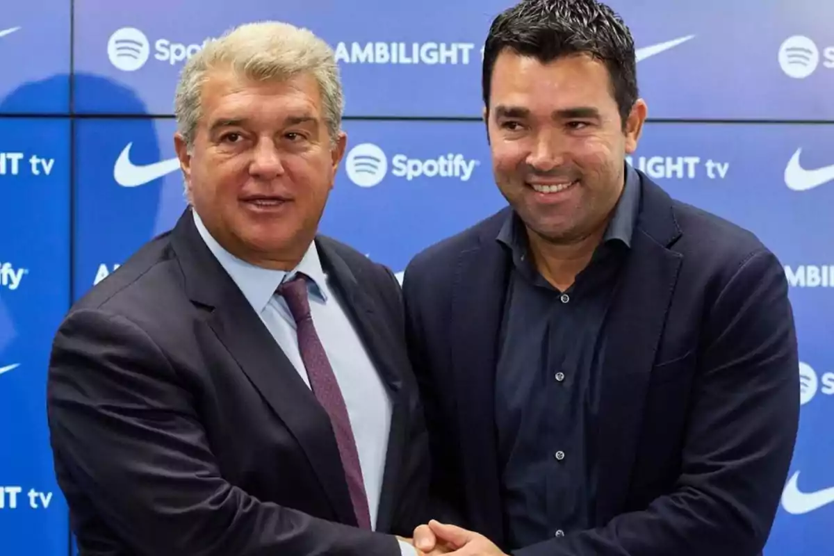 Dos hombres de traje se dan la mano frente a un fondo azul con logotipos de marcas. Dos hombres de traje se dan la mano frente a un fondo azul con logotipos de marcas.