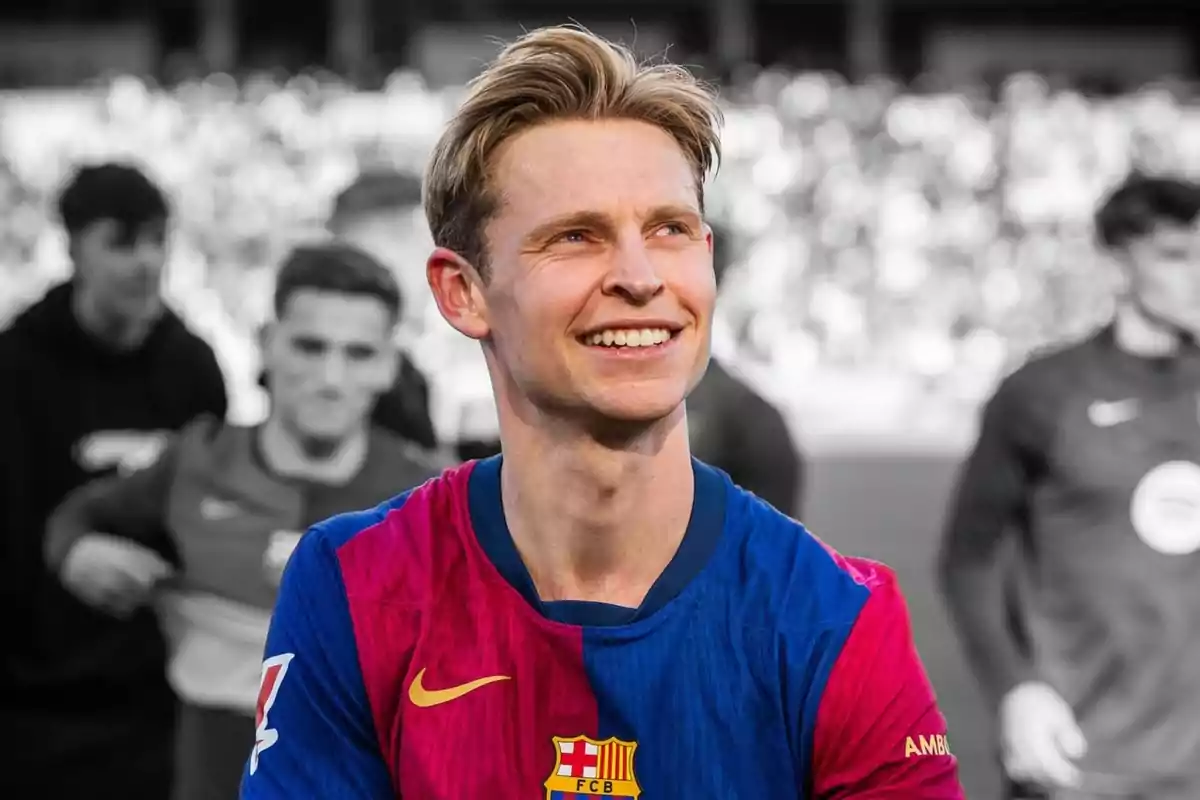 A player smiles while wearing a blue and red jersey on a field with blurred people in the background. A player smiles while wearing a blue and red jersey on a field with blurred people in the background.