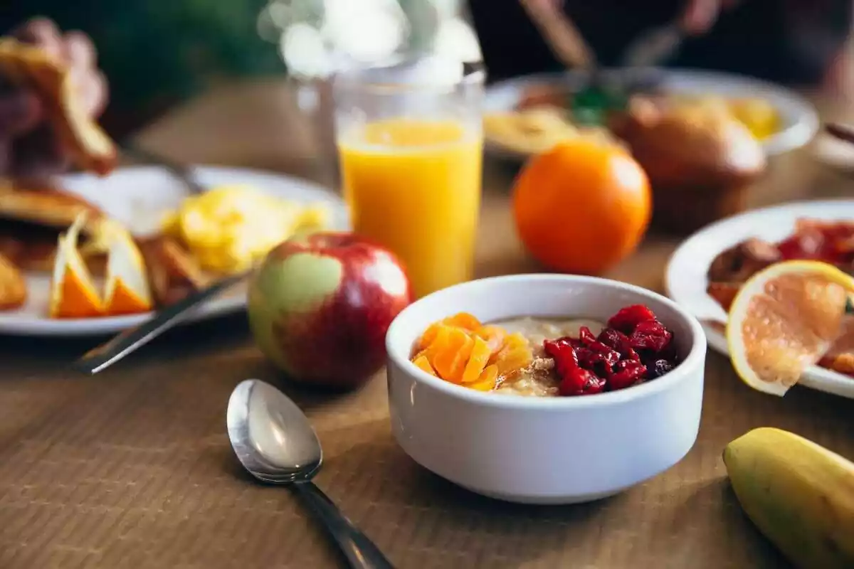 Diversos plats de menjar per esmorzar amb algunes fruites i un suc de taronja