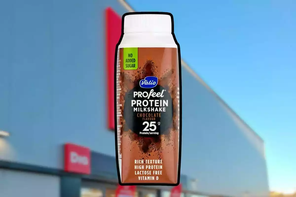 Una ampolla de batut de proteïnes amb gust de xocolata, sense sucre afegit, davant d'un edifici amb cel blau de fons. Una ampolla de batut de proteïnes amb gust de xocolata, sense sucre afegit, davant d'un edifici amb cel blau de fons.