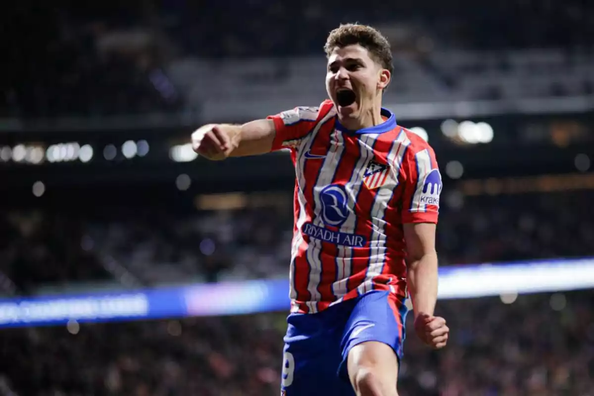 A soccer player celebrating a goal with enthusiasm in a floodlit stadium.