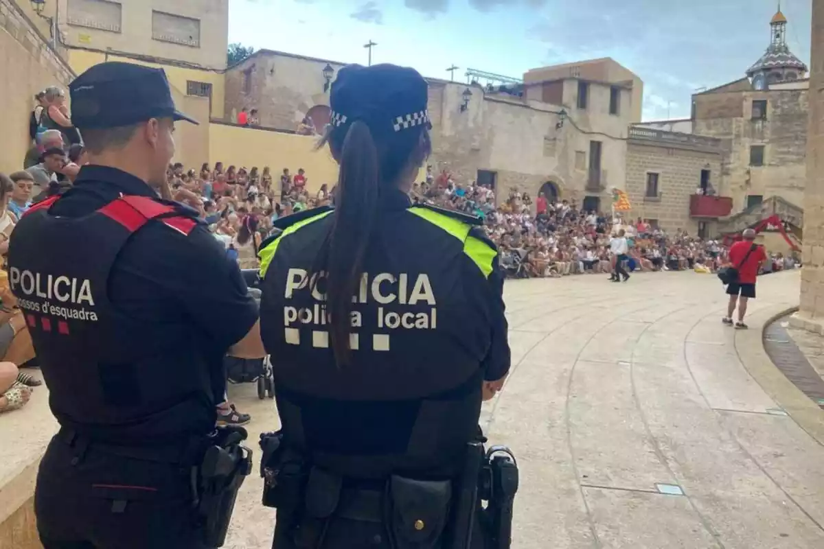 Imatge d'un Mosso i una policia local d'esquenes vigilant un acte d'una festa major de Catalunya
