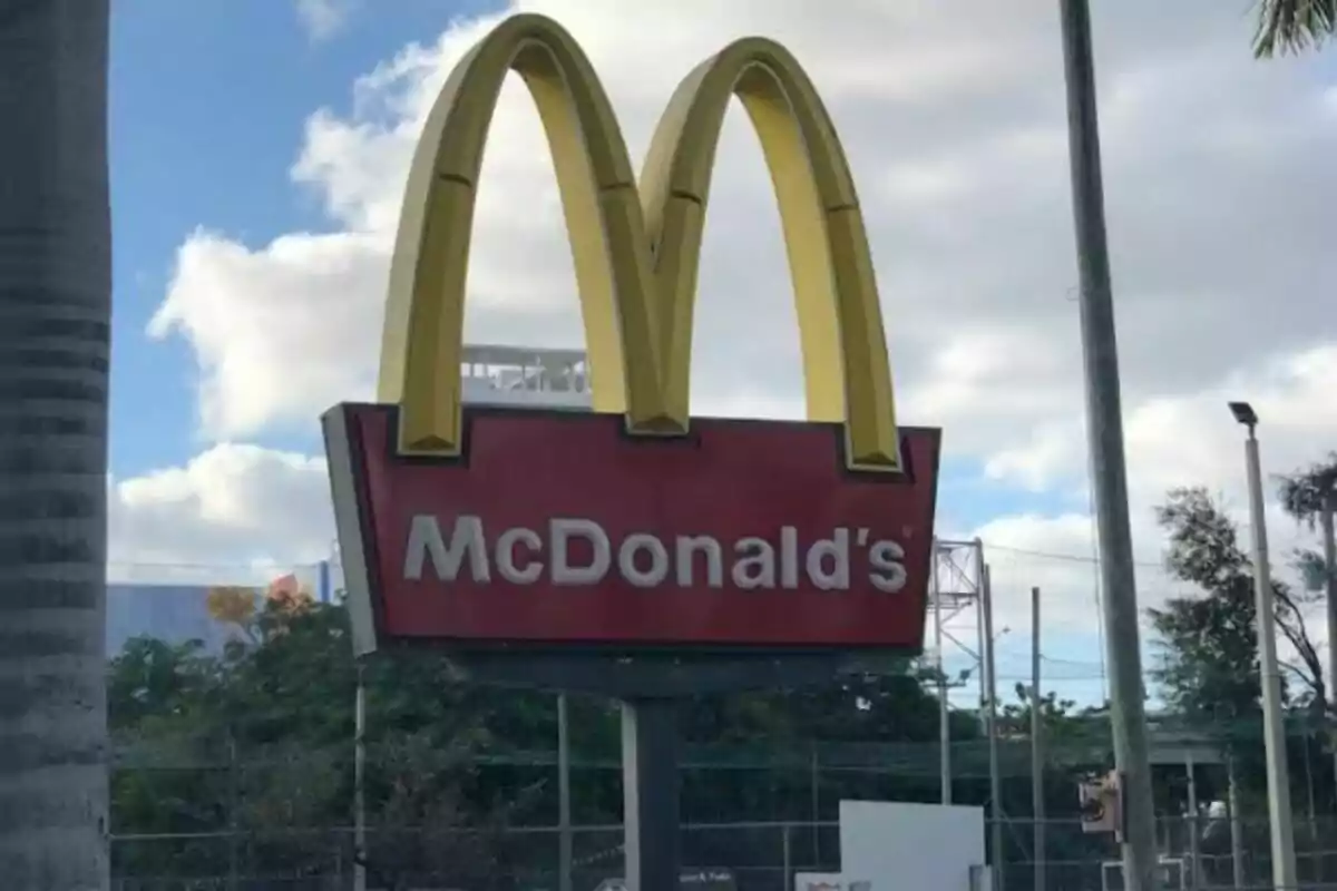 McDonald's sign with the iconic golden arches logo against a cloudy sky background McDonald's sign with the iconic golden arches logo against a cloudy sky background