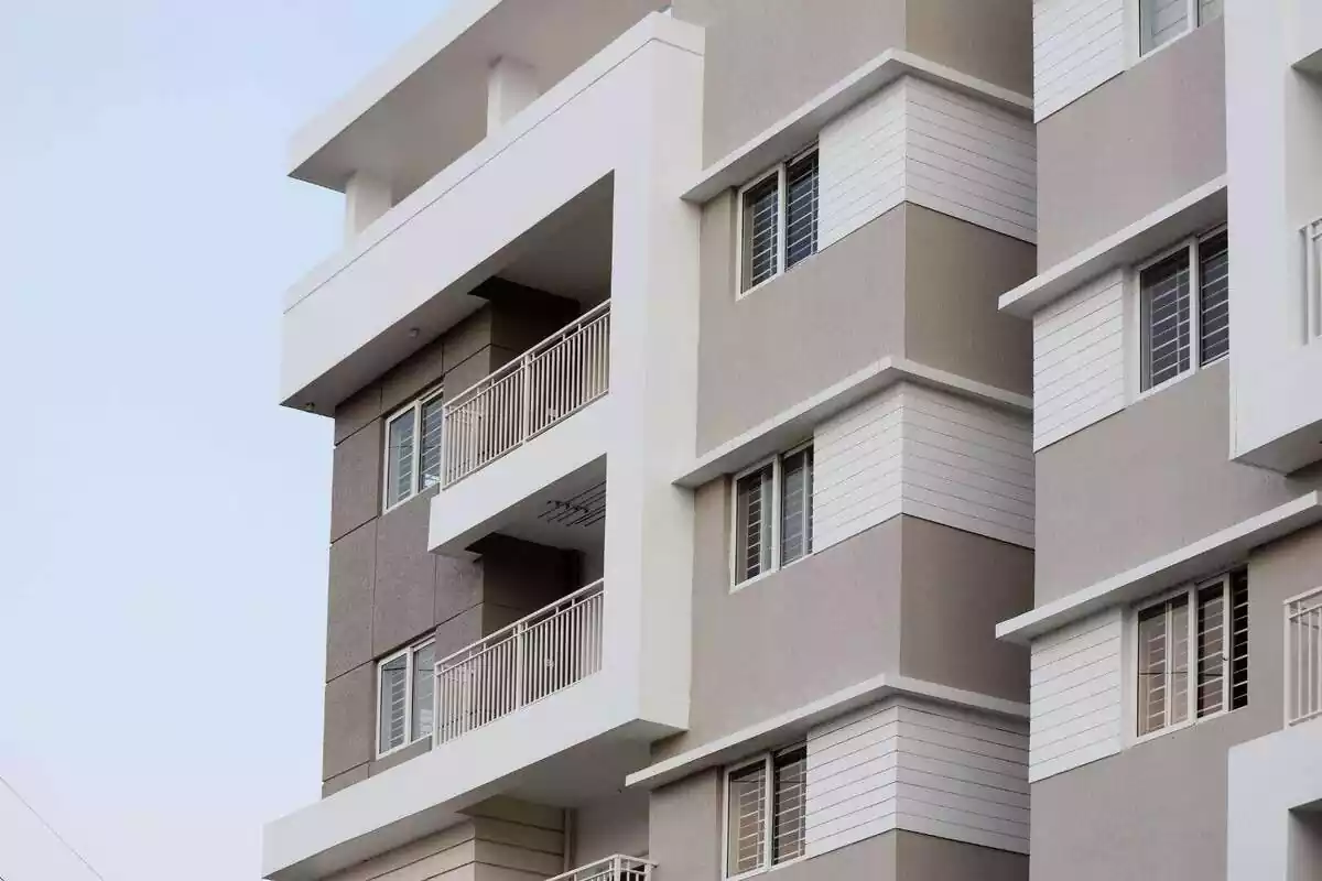 Exterior d'un bloc de pisos de color gris i blanc amb balcons y finestres