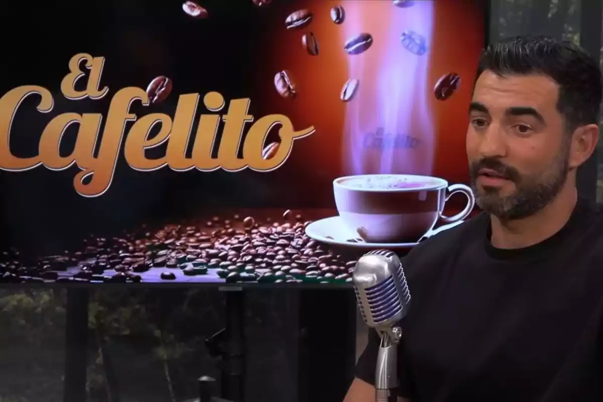 A dark-haired, bearded man speaks in front of a silver microphone with a screen behind him displaying the El Cafelito logo, coffee beans, and a steaming cup. A dark-haired, bearded man speaks in front of a silver microphone with a screen behind him displaying the El Cafelito logo, coffee beans, and a steaming cup.