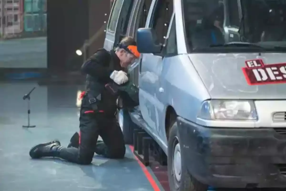 Manuel Díaz 'El Cordobés' amb equip de protecció intenta obrir la porta d'una furgoneta en un escenari.