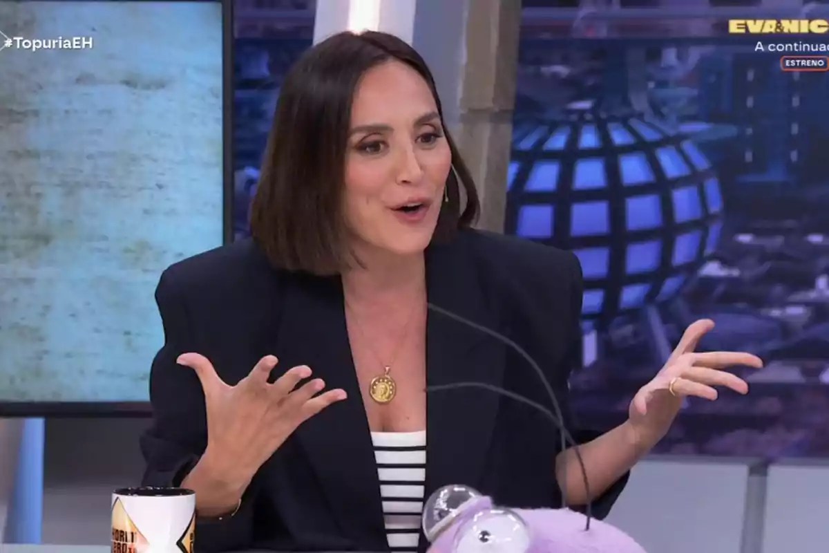 Tamara Falcó està gesticulant mentre parla en un programa de televisió, porta un collaret daurat i una jaqueta fosca, i hi ha una tassa i un objecte morat a la taula davant d'ella. Captura de 'El Hormiguero'. Tamara Falcó està gesticulant mentre parla en un programa de televisió, porta un collaret daurat i una jaqueta fosca, i hi ha una tassa i un objecte morat a la taula davant d'ella. Captura de 'El Hormiguero'.