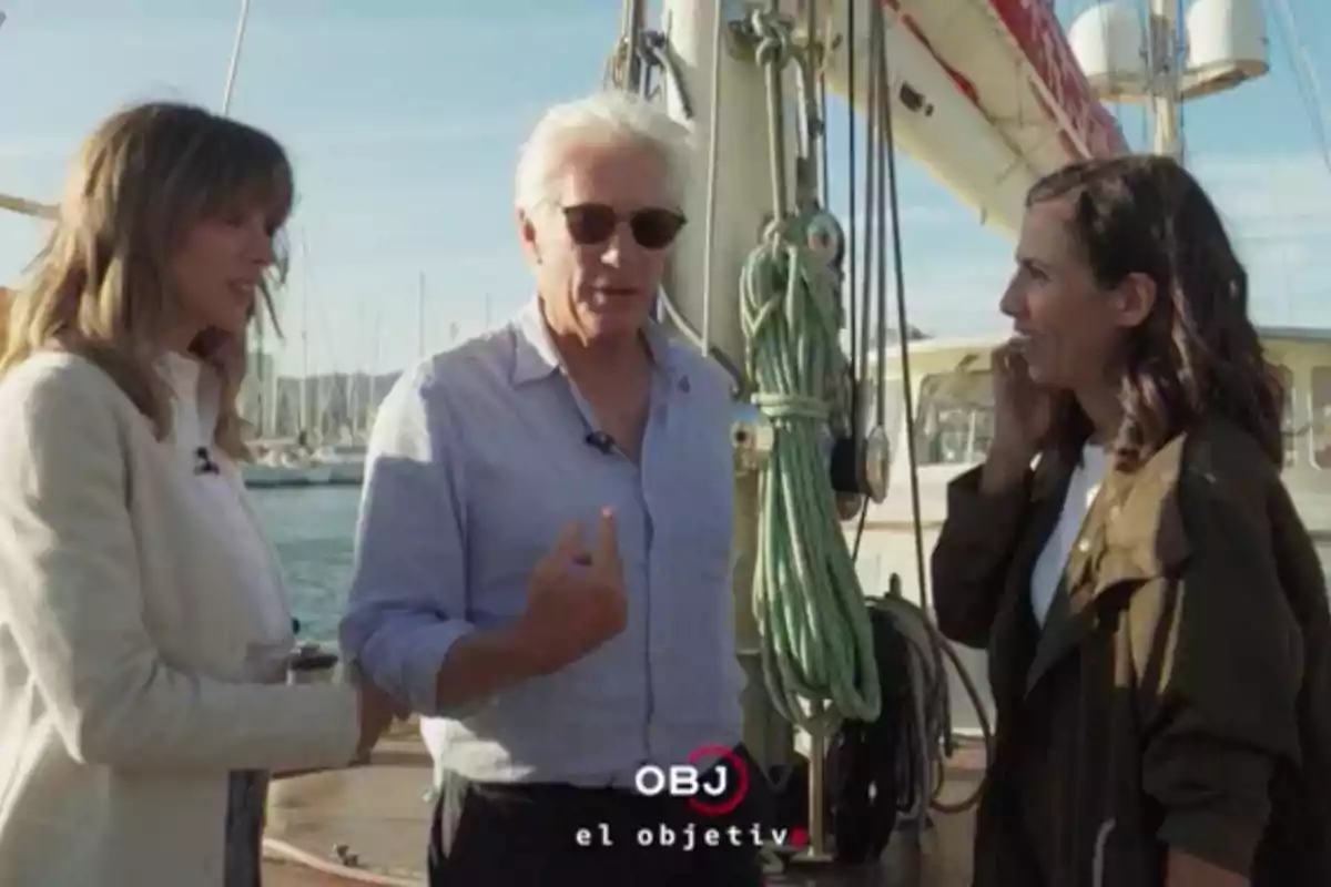 Alejandra Silva, Richard Gere, and Ana Pastor converse on the deck of a ship with ropes and masts visible in the background. Screenshot from 'El Objetivo'. Alejandra Silva, Richard Gere, and Ana Pastor converse on the deck of a ship with ropes and masts visible in the background. Screenshot from 'El Objetivo'.