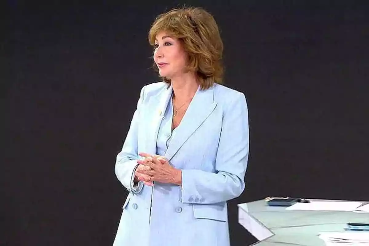 Ana Rosa Quintana amb vestit blau clar dempeus al costat d'una taula en un estudi. Captura de 'El Programa de AR' Ana Rosa Quintana amb vestit blau clar dempeus al costat d'una taula en un estudi. Captura de 'El Programa de AR'