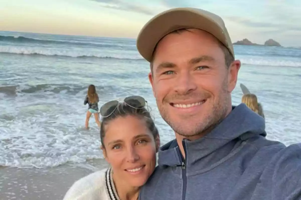 Una parella, formada per l’Elsa Pataky i en Chris Hemsworth, somrient fent-se una selfie a la platja amb dues nenes jugant a prop del mar al capvespre. Una parella, formada per l’Elsa Pataky i en Chris Hemsworth, somrient fent-se una selfie a la platja amb dues nenes jugant a prop del mar al capvespre.
