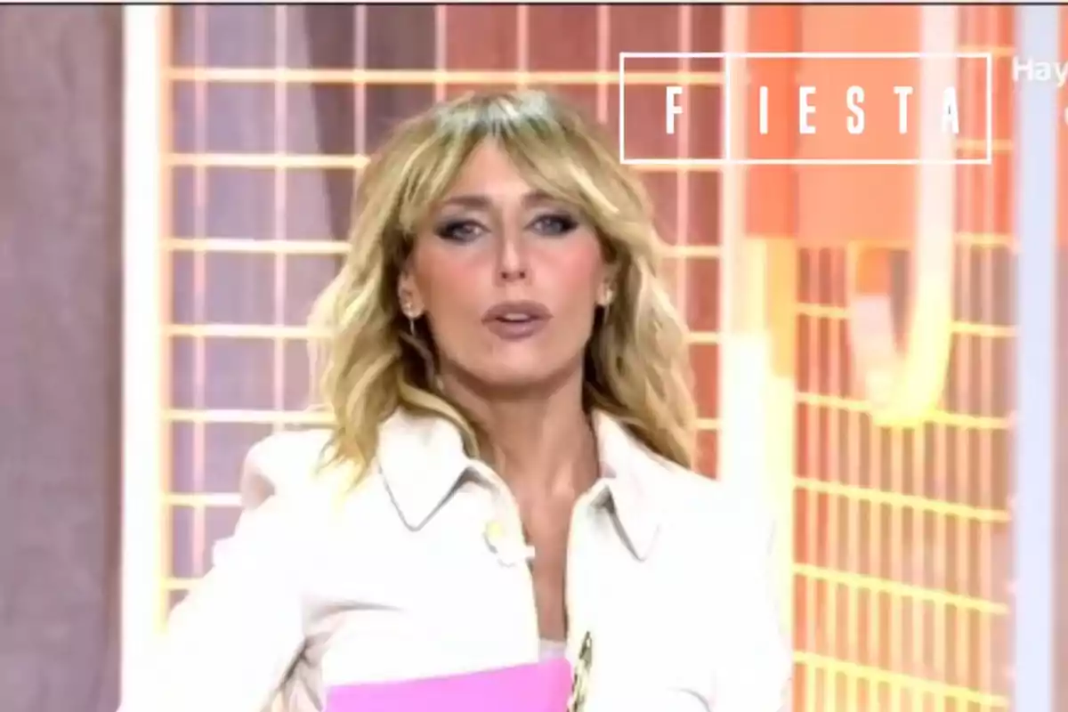 Emma García amb jaqueta blanca i els cabells llargs rossos, amb el logotip del programa 'Fiesta'