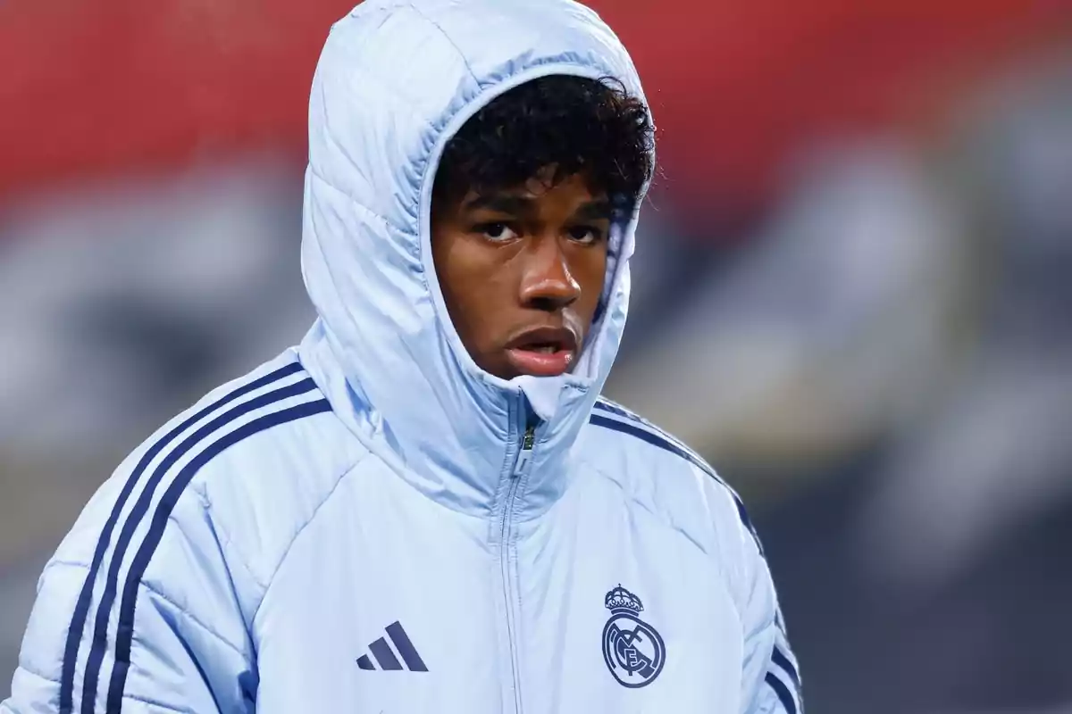 A football player in a white jacket and hood during training.