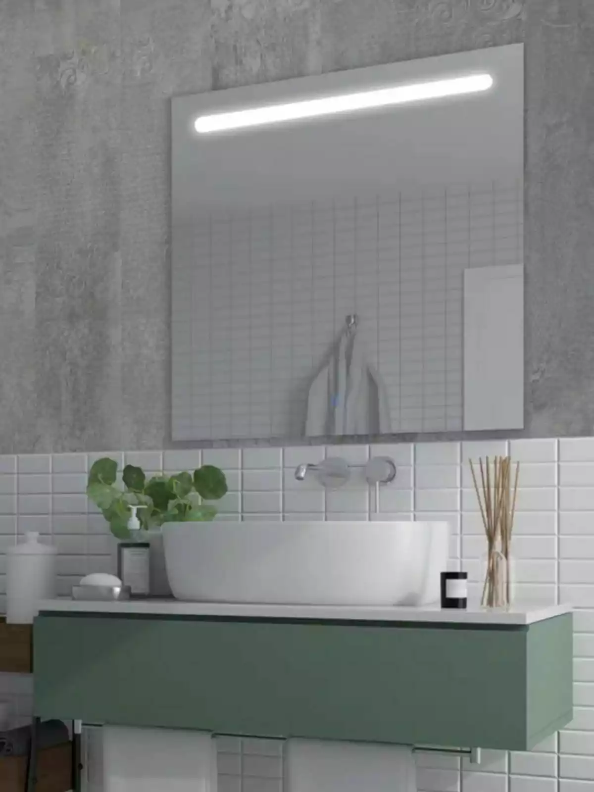 Un baño moderno con un lavabo blanco sobre un mueble verde, un espejo grande con luz integrada de Leroy Merlin y detalles decorativos como plantas y difusores de aroma.