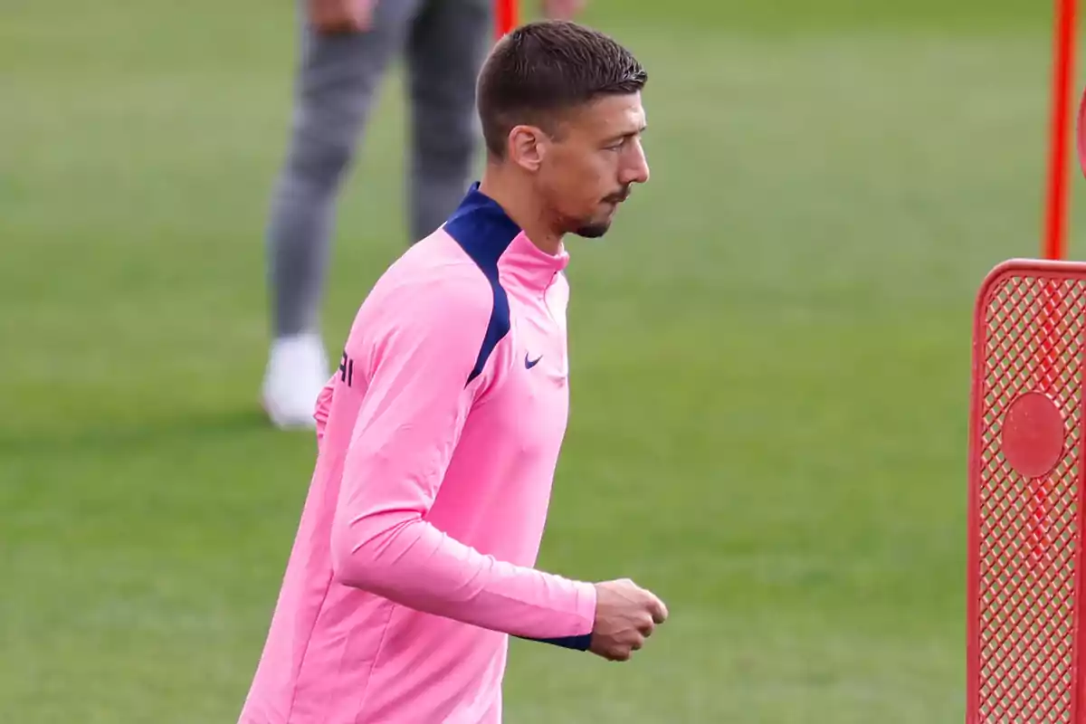 A soccer player in a pink sweatshirt training on a soccer field. A soccer player in a pink sweatshirt training on a soccer field.