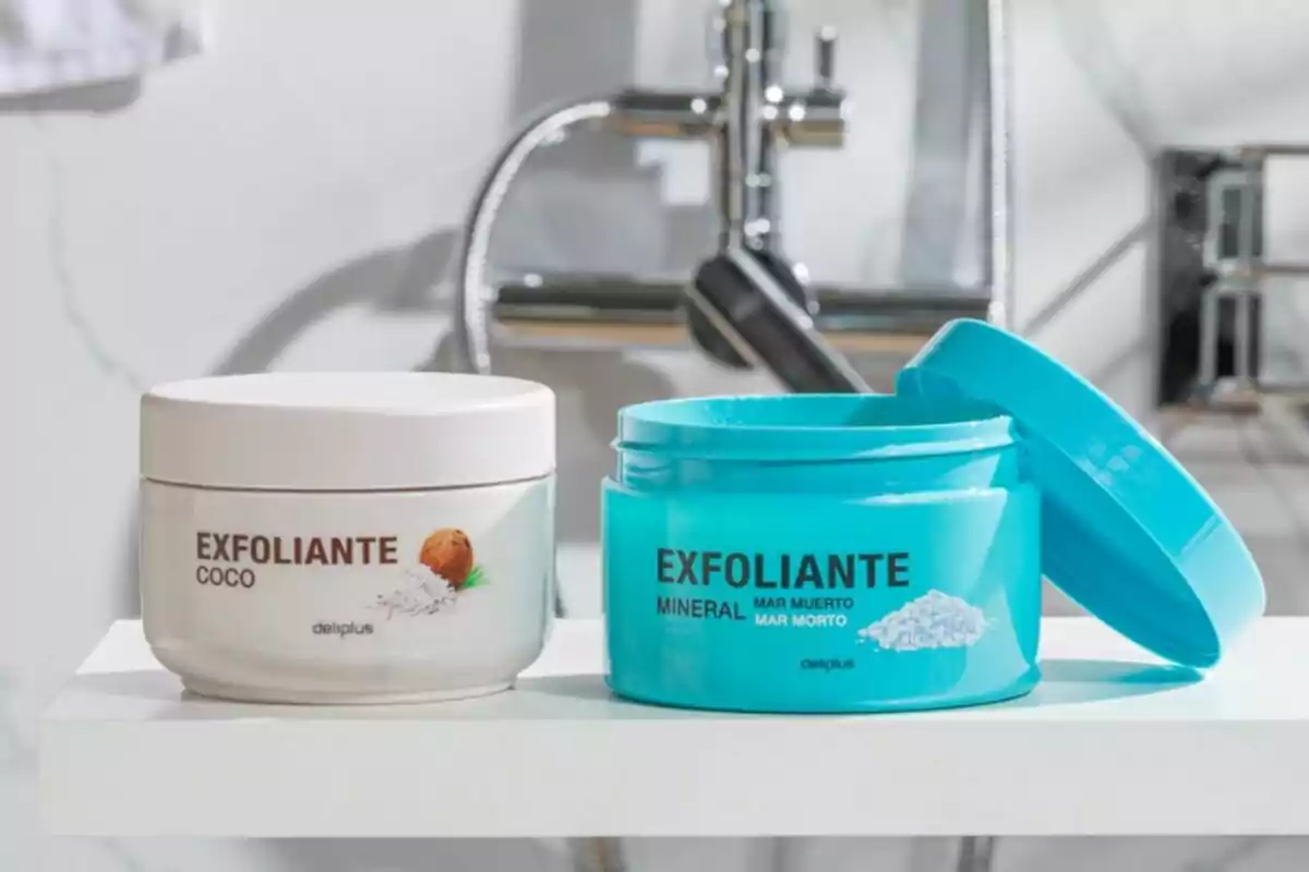 Dos envasos d'exfoliants Deliplus, un de coco i un altre mineral, sobre una superfície blanca amb una aixeta de fons.