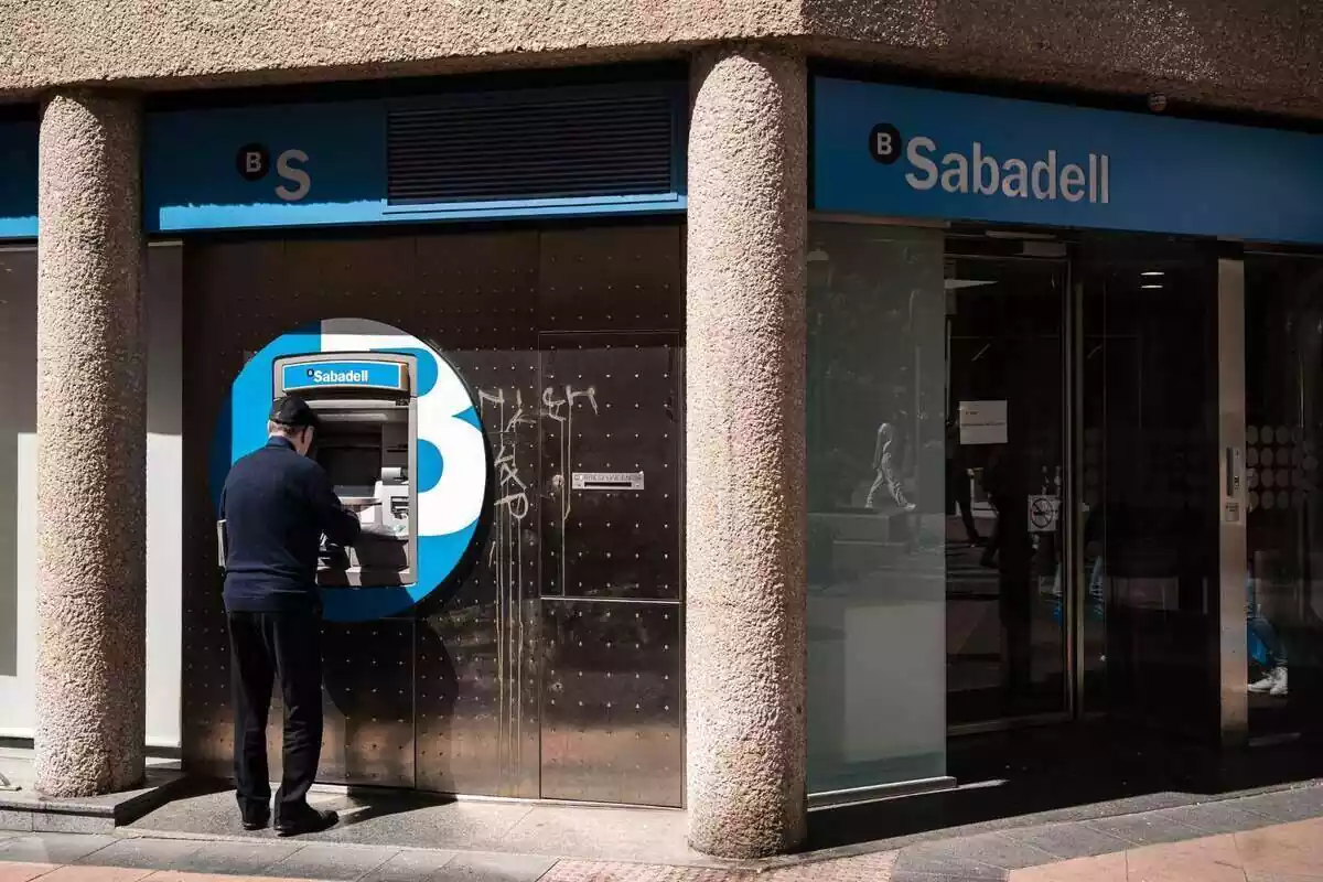 Ancià utilitzant el caixer automàtic exterior del banc Sabadell