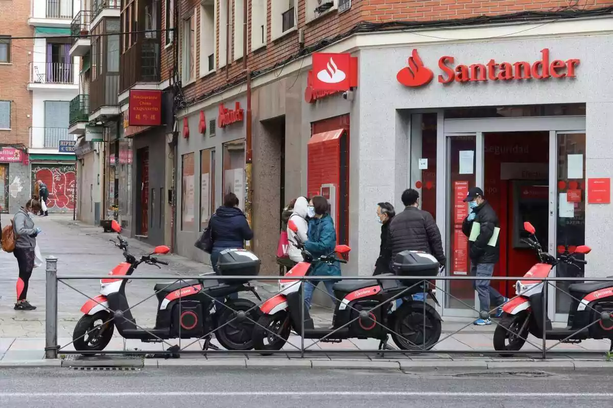 Varies persones esperant amb mascareta per entrar al Banc Santander