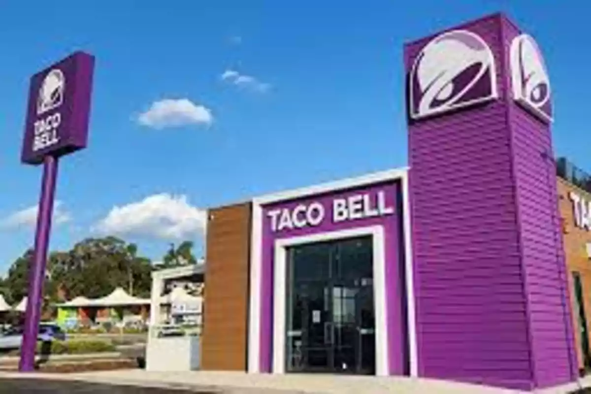 Frente de un restaurante de comida rápida Taco Bell con un diseño moderno y colores morado y blanco. Frente de un restaurante de comida rápida Taco Bell con un diseño moderno y colores morado y blanco.