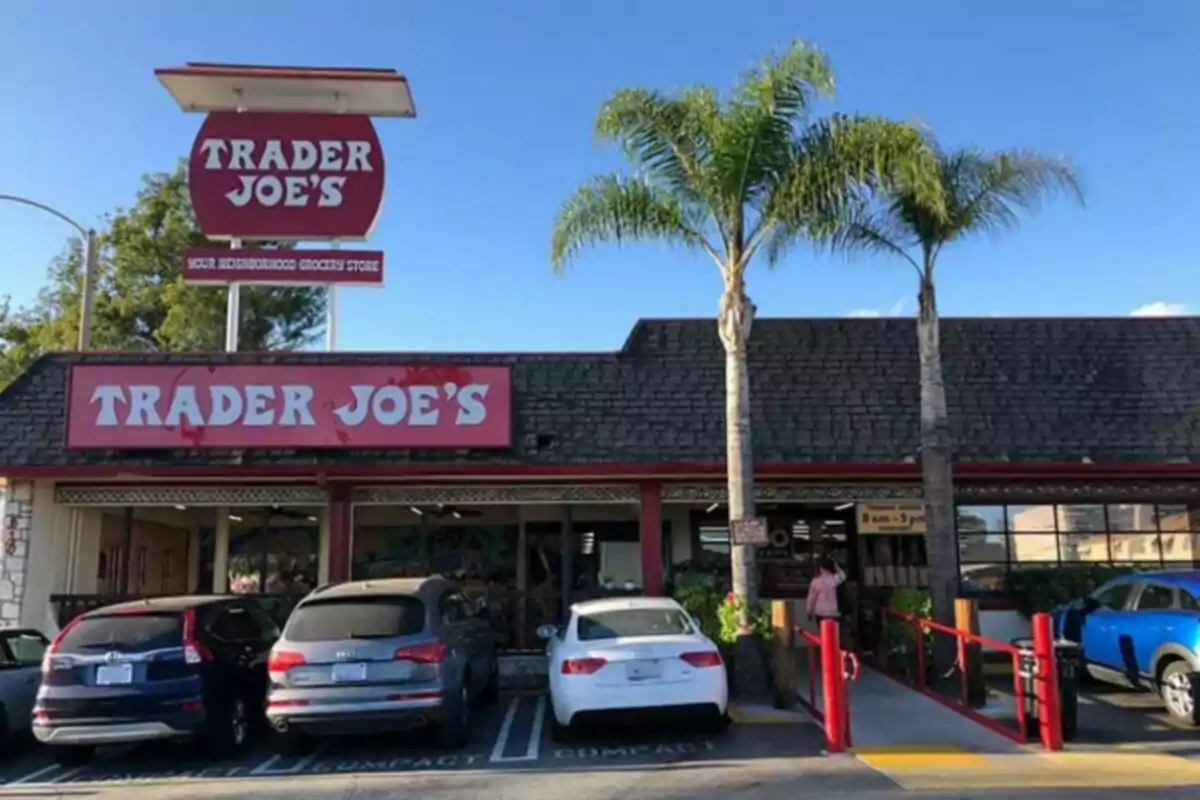 Facade of a Trader Joe's store with cars parked in front and two palm trees next to the entrance