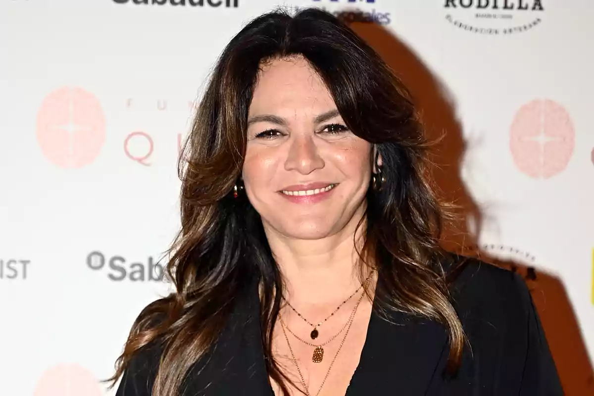 Fabiola Martínez, vestida de negre i somrient davant d’un fons amb logotips de marques. Fabiola Martínez, vestida de negre i somrient davant d’un fons amb logotips de marques.