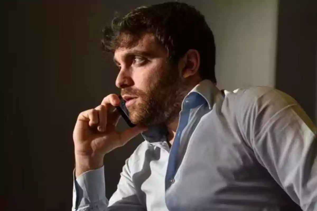 Bearded man talking on mobile phone while wearing a light blue shirt. Bearded man talking on mobile phone while wearing a light blue shirt.