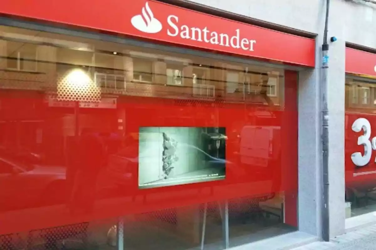 Fachada de una sucursal del banco Santander con un letrero rojo y un logotipo blanco.