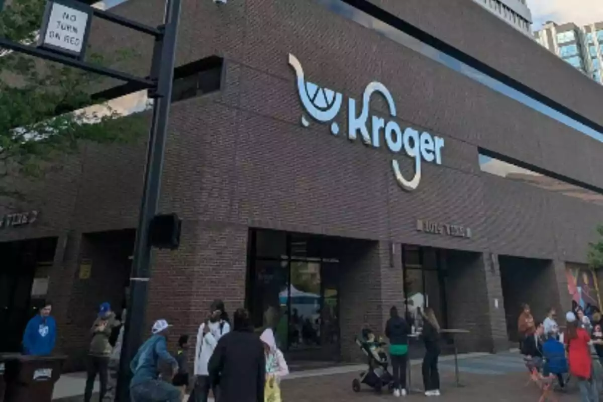 Facade of a Kroger store with several people gathered at the entrance. Facade of a Kroger store with several people gathered at the entrance.
