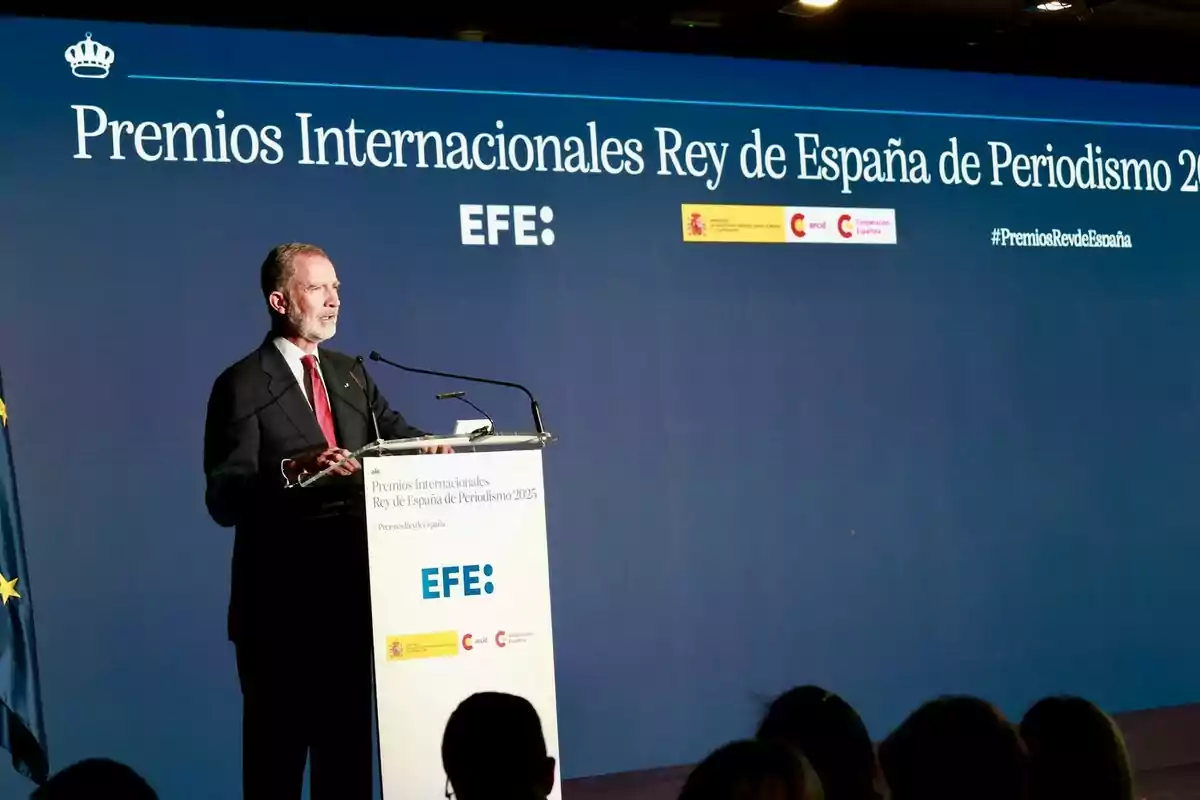 Felip VI amb vestit fosc fa un discurs en un faristol durant la cerimònia dels Premis Internacionals Rei d’Espanya de Periodisme 2025, amb un fons blau que mostra el nom de l’esdeveniment i logotips institucionals. Felip VI amb vestit fosc fa un discurs en un faristol durant la cerimònia dels Premis Internacionals Rei d’Espanya de Periodisme 2025, amb un fons blau que mostra el nom de l’esdeveniment i logotips institucionals.