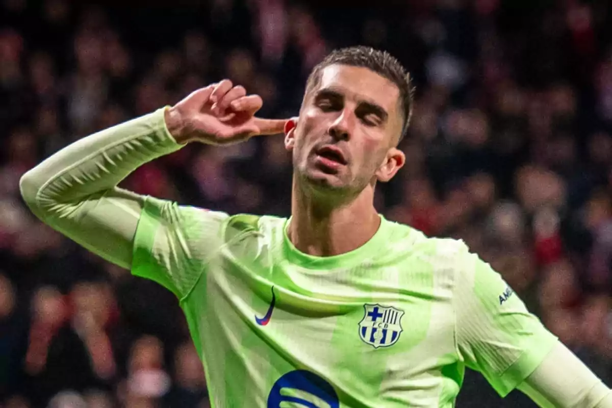 Un jugador de fútbol con uniforme verde claro celebra llevándose la mano a la oreja en un estadio lleno de espectadores. Un jugador de fútbol con uniforme verde claro celebra llevándose la mano a la oreja en un estadio lleno de espectadores.