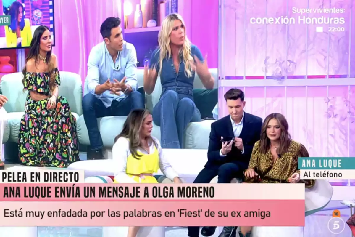 Un grup de persones està assegut en un plató de televisió amb una decoració en tons rosats i morats, mentre discuteixen un tema que apareix en un rètol a la part inferior de la imatge. Un grup de persones està assegut en un plató de televisió amb una decoració en tons rosats i morats, mentre discuteixen un tema que apareix en un rètol a la part inferior de la imatge.