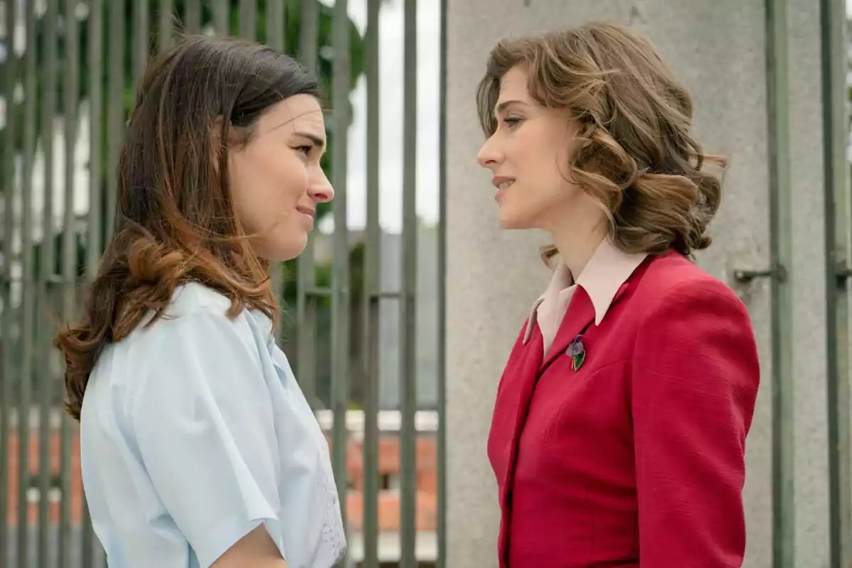 Fotografia de Marta Belmonte i Alba Brunet davant d'una reixa, una vestida amb una camisa blanca i l'altra amb un vestit vermell a Sueños de Libertad